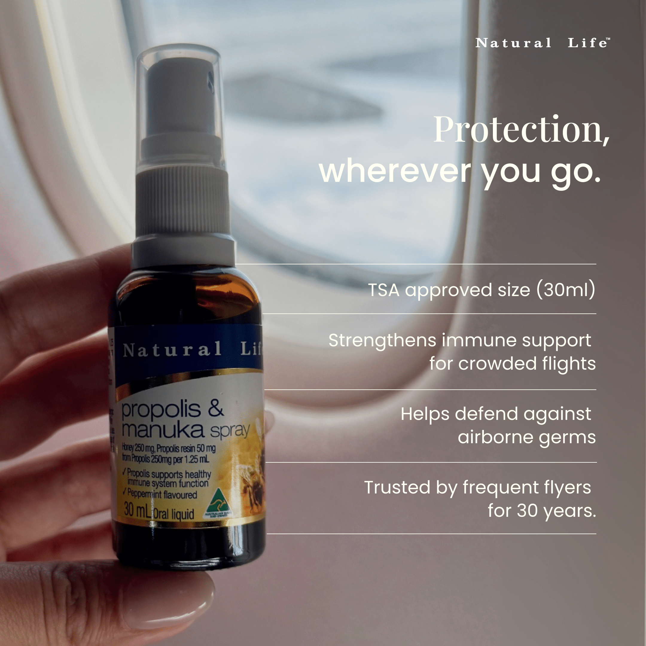 Bottle of Natural Life propolis and manuka spray held by a hand on an airplane.